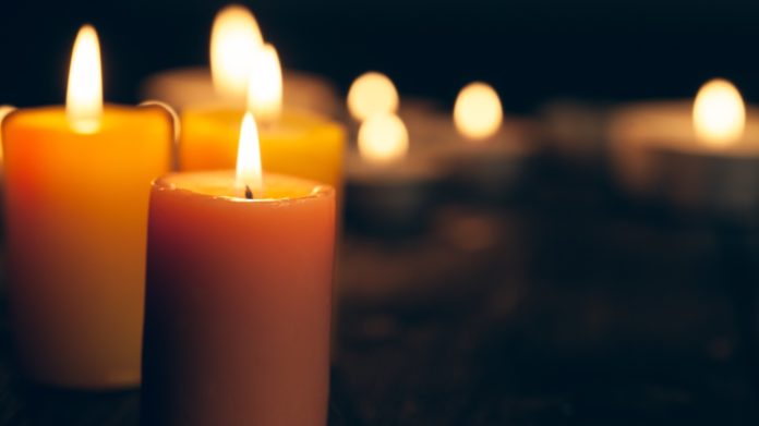 candles burning in darkness over black background. commemoration concept. VigilCandles thegrio.com