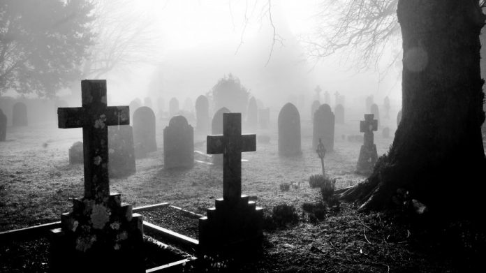 black and white photograph of an English grave yard covered in thick fog